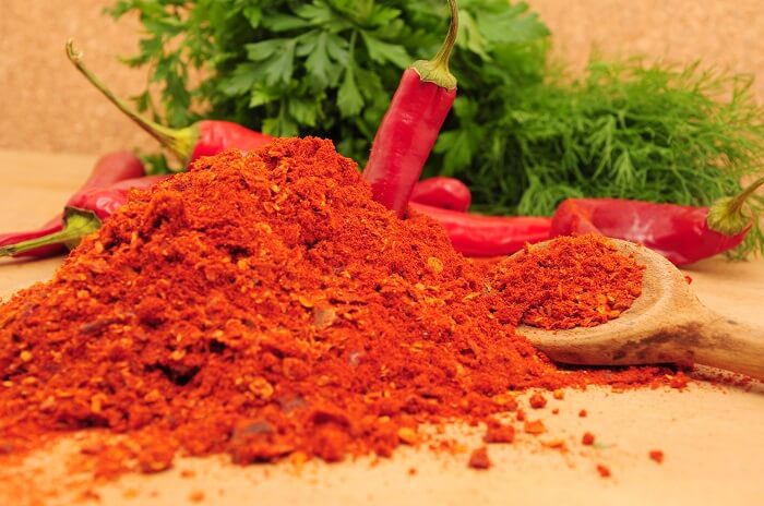 picture of cayenne pepper powder next to actual peppers